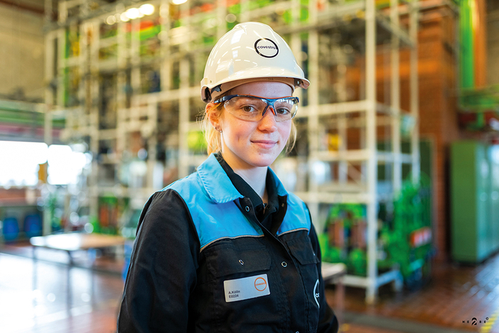 Junge Frau mit Helm und Schutzbrille in Werkshalle Junge Frau mit Helm und Schutzbrille in Werkshalle