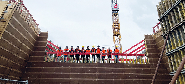 Mitarbeitende von Becker Bauunternehmen mit Westen und Helm auf einer Baustelle Mitarbeitende von Becker Bauunternehmen mit Westen und Helm auf einer Baustelle