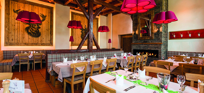 Eingedeckte Tische im urig eingerichteten Hotel-Restaurant Hirsch, im Hintergrund Kaminfeuer 