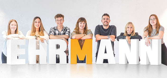 EHRMANN in Buchstaben, dahinter mehrere Personen EHRMANN in Buchstaben, dahinter mehrere Personen