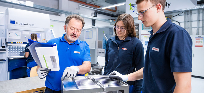 Drei Personen arbeiten an einem technischen Gerät.