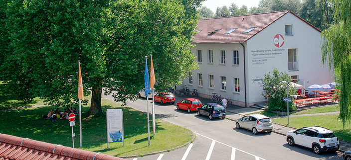 Das Gebäude der Bernd Blindow Gruppe in Friedrichshafen mit grünen Bäumen und geparkten Autos davor Das Gebäude der Bernd Blindow Gruppe in Friedrichshafen mit grünen Bäumen und geparkten Autos davor