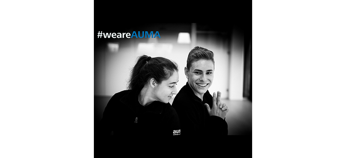 Schwarzweißbild von zwei jungen lächelnden Menschen mit AUMA-Logo auf dem Pullover, Bildaufschrift: #weareAUMA Schwarzweißbild von zwei jungen lächelnden Menschen mit AUMA-Logo auf dem Pullover, Bildaufschrift: #weareAUMA