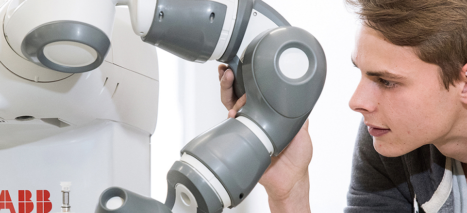 Person schaut sich einen kleinen Roboter an.