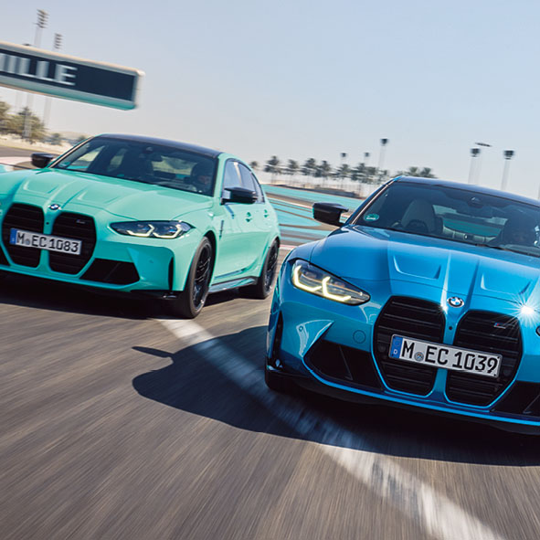 Ein blauer und ein türkiser BMW fahren auf einer Teststrecke