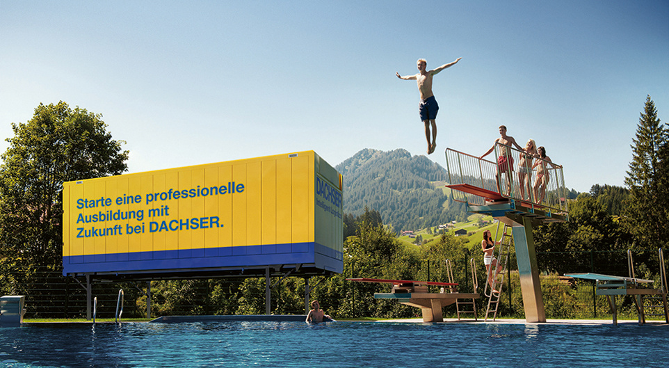 Junger Mann springt vom Sprungbrett in den See - Container von Dachser steht im Hintergrund