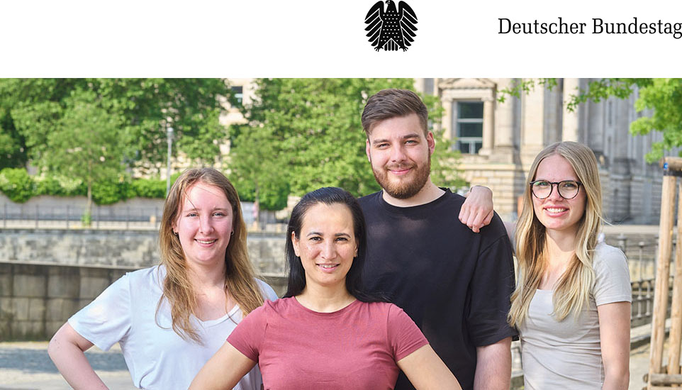 Vier junge lächelnde Menschen vor dem Reichstagsgebäude