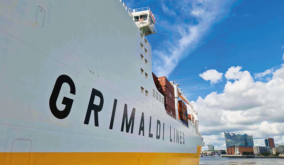 Seitliche Ansicht eines GRIMALDI-Containerschiffs mit der Hamburger Harmonie im Hintergrund