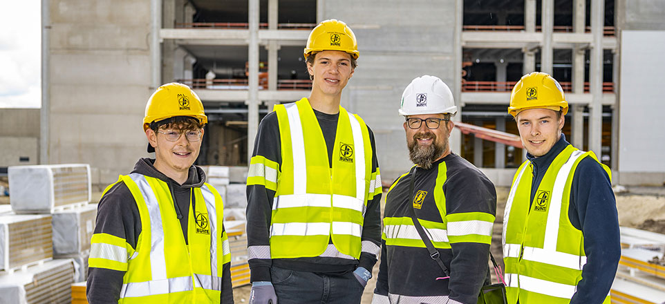 Vier Personen mit Schutzhelm auf einer Baustelle.