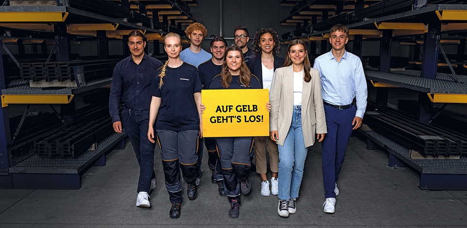 Jugendliche laufen auf Kamera zu. Junge Frau in der Mitte hält ein gelbes Schild in der Hand mit der Aufschrift "AUF GELB GEHTS LOS!"