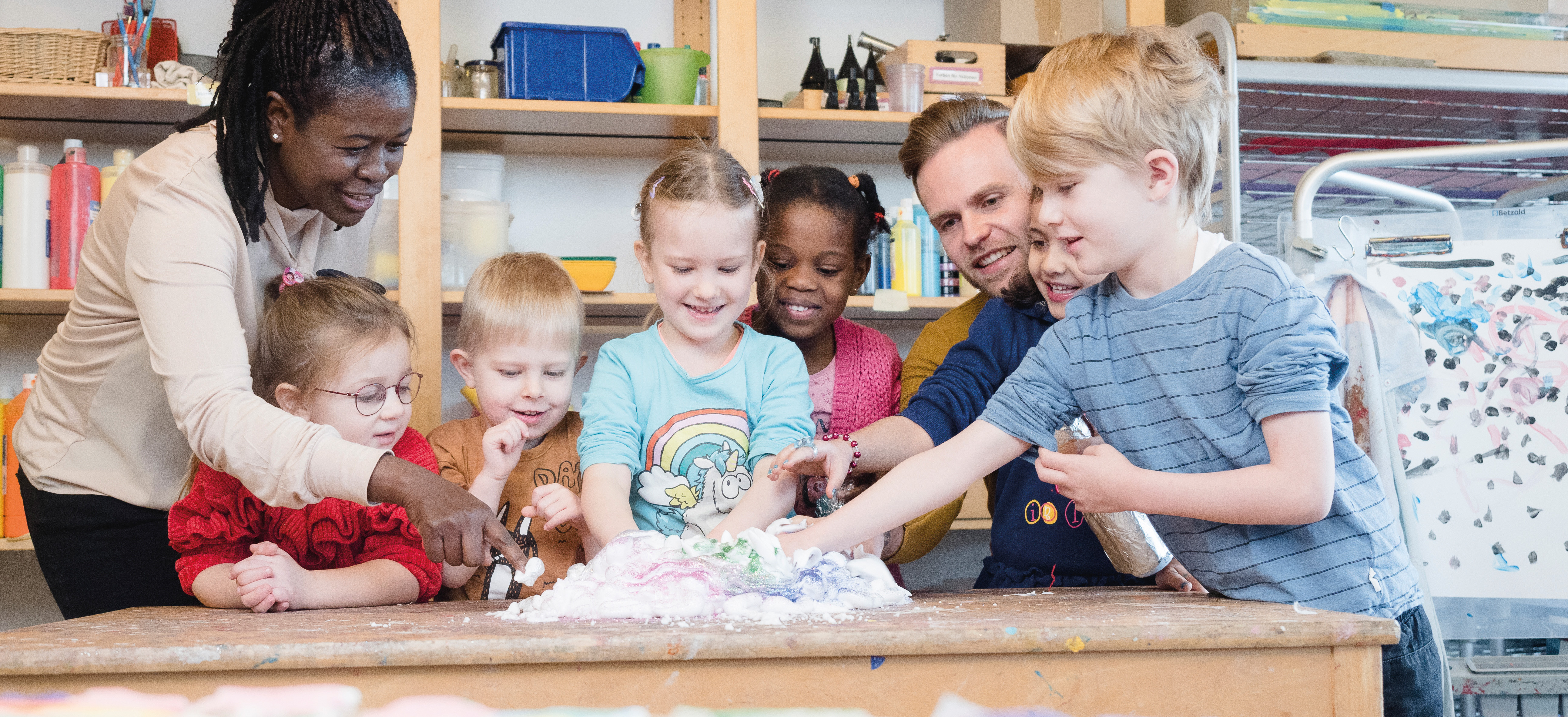 Kindergruppe mit Erzieherin bei einem Experiment. 