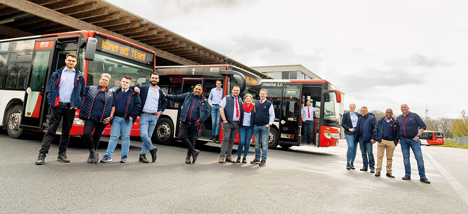 Mitarbeitende stehen in Gruppen vor Bussen