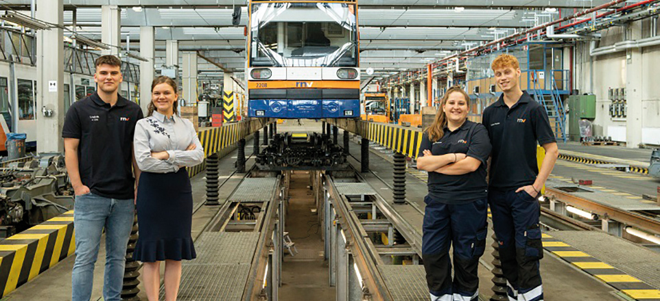 4 Personen stehen in einer Werkshalle 4 Personen stehen in einer Werkshalle