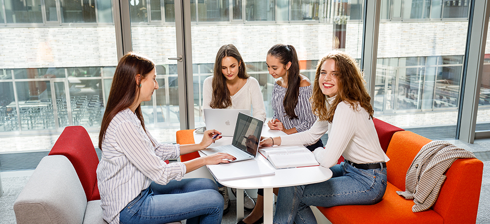 Vierer Personengruppe sitzt zusammen an einem Tisch und liest in Büchern. Vierer Personengruppe sitzt zusammen an einem Tisch und liest in Büchern.
