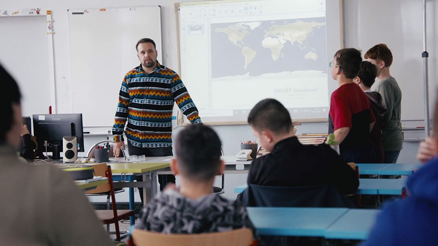 Lehrer im Klassenzimmer mit Schülerinen und Schülern.